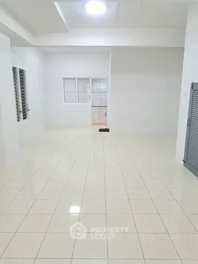 Spacious empty room with tiled flooring and white walls, ideal for customization.