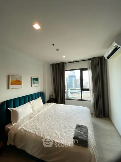 Spacious bedroom with city view, modern decor, and natural light.