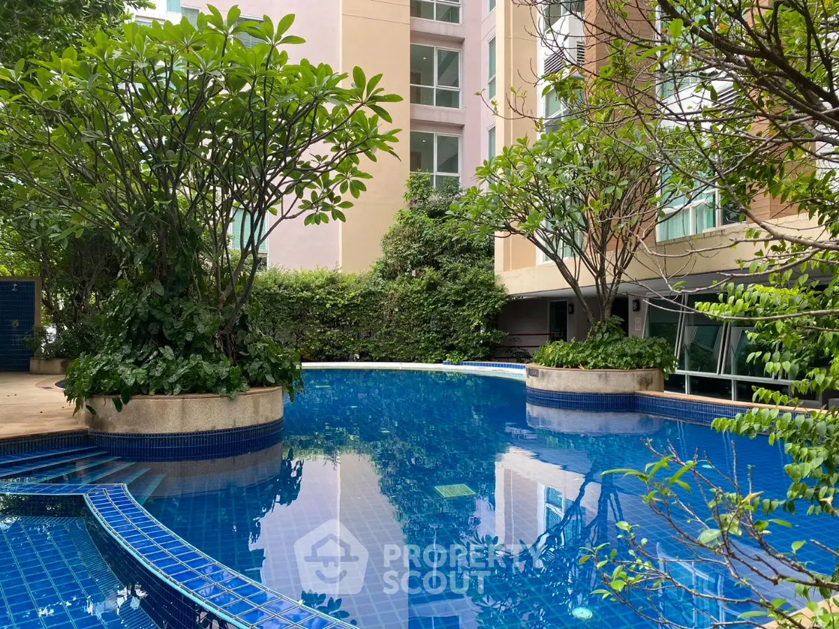 Luxurious residential pool surrounded by lush greenery and modern architecture.