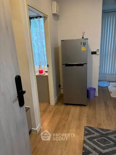 Modern apartment interior with sleek fridge and wooden flooring