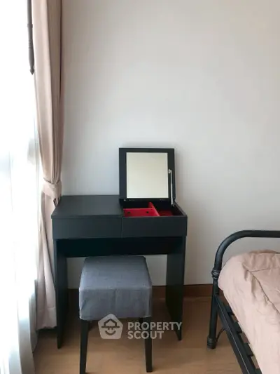 Cozy bedroom corner with stylish black vanity and stool, perfect for modern living.