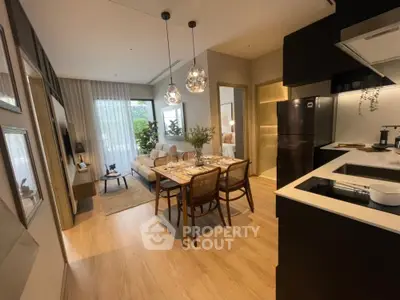 Modern open-plan kitchen with sleek black appliances flows into a cozy dining area, complemented by stylish pendant lighting and warm wooden flooring.