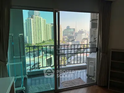 Stunning city view from a modern apartment balcony with glass doors.