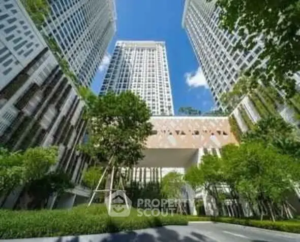 Stunning modern high-rise buildings with lush greenery and clear blue sky.