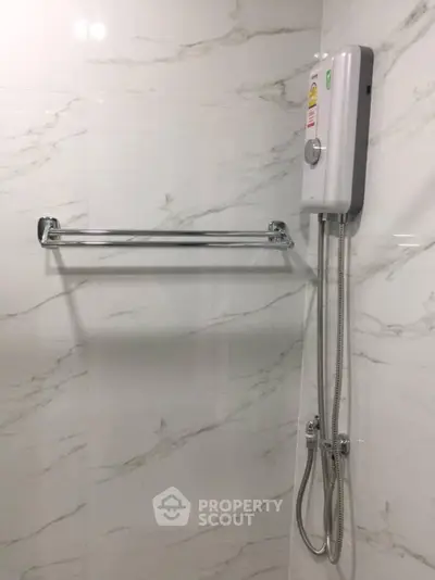 Modern bathroom with sleek shower heater and towel rack on marble wall.