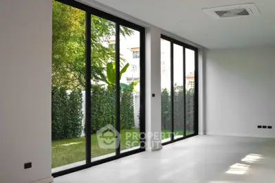 Spacious modern living room with large glass doors opening to a lush garden view.