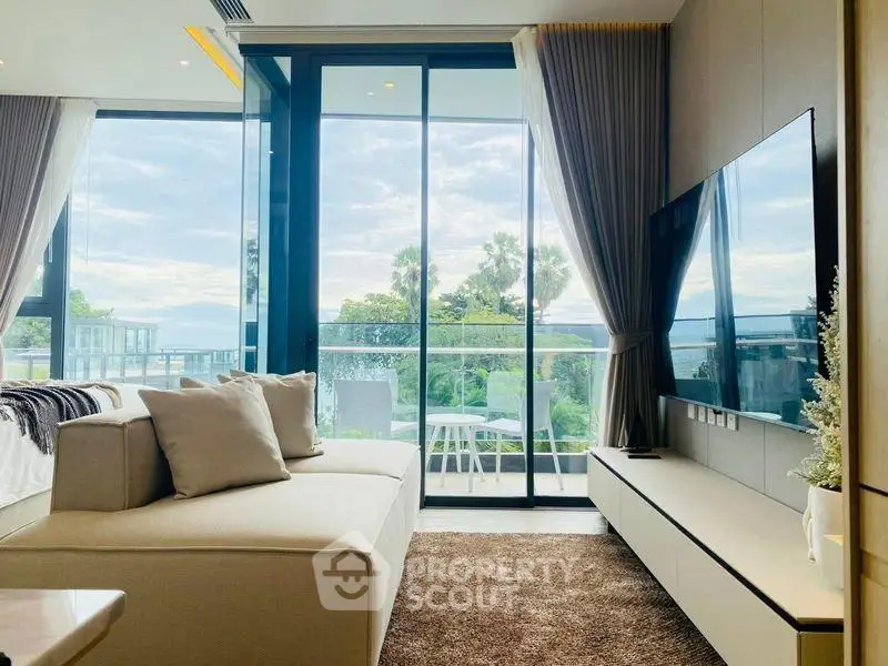 Luxurious living room with large windows offering stunning views of lush greenery and a spacious balcony.