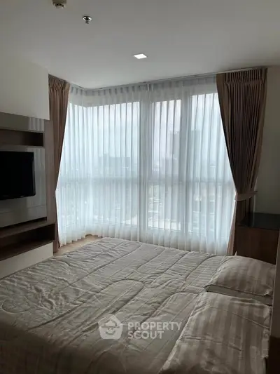 Spacious bedroom with large windows and modern decor in a high-rise apartment.