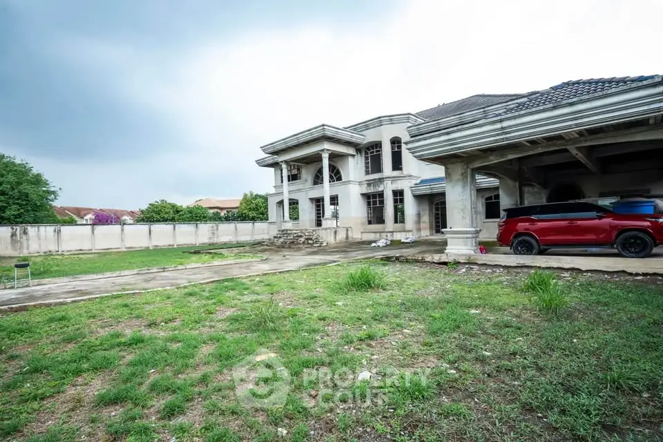 Spacious luxury home with expansive garden and modern architecture, featuring a sleek red car in the driveway.
