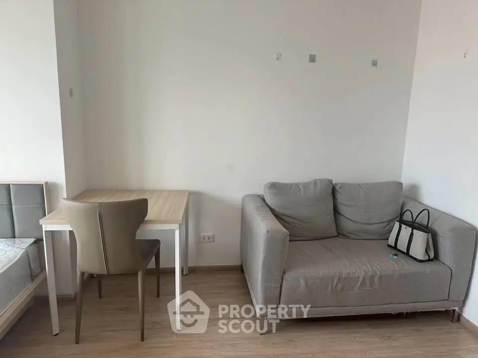 Cozy living area with modern sofa and study desk in a minimalist apartment.