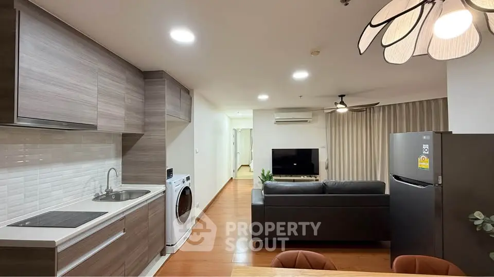 Modern open-layout living room with kitchen, featuring sleek appliances and cozy seating area.