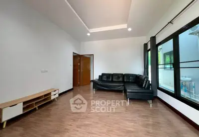 Spacious living room with modern black leather sofa and large windows
