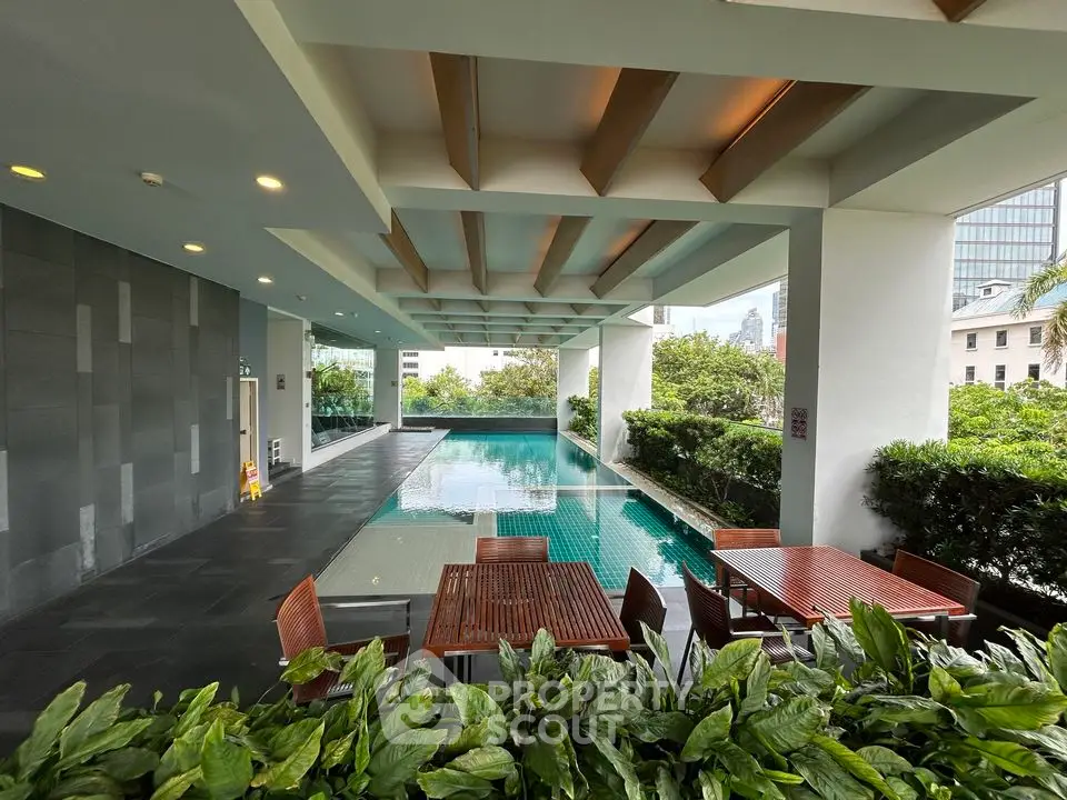Luxurious poolside area with modern seating and lush greenery in a high-end residential complex.