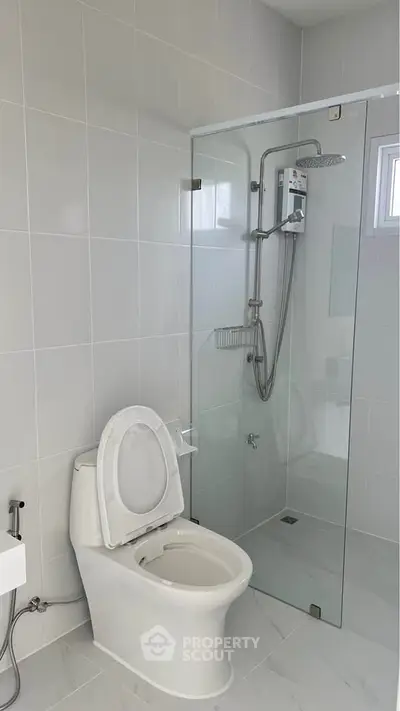 Modern bathroom with glass shower enclosure and sleek white fixtures.