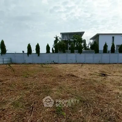 Spacious plot of land with modern homes in the background, ideal for new construction.