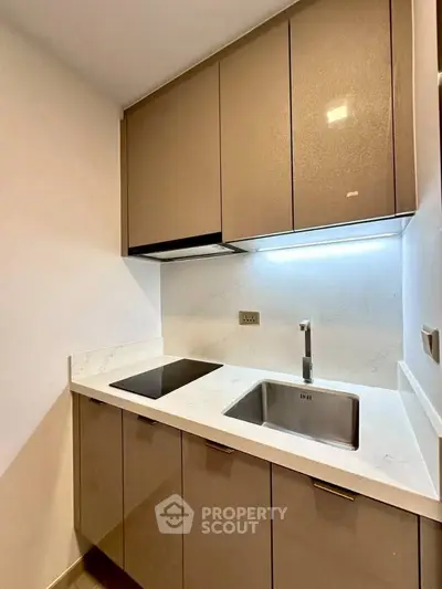 Modern compact kitchen with sleek cabinets and built-in stovetop