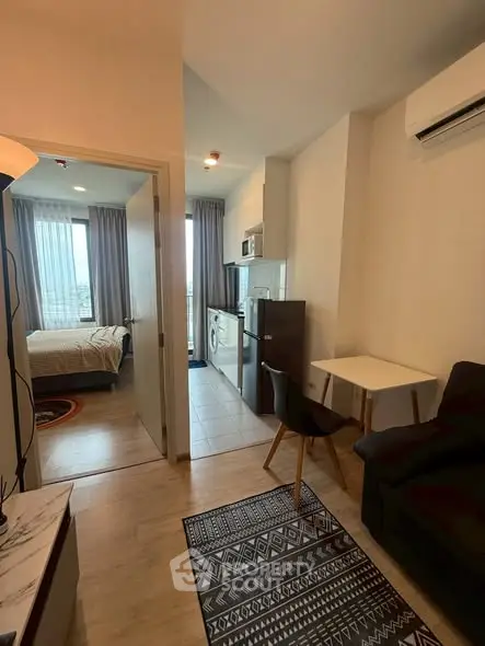 Modern apartment interior with compact living space and bedroom view.