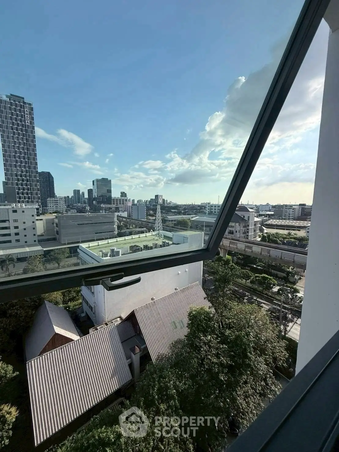 Stunning cityscape view from a modern apartment window, showcasing urban skyline and greenery.
