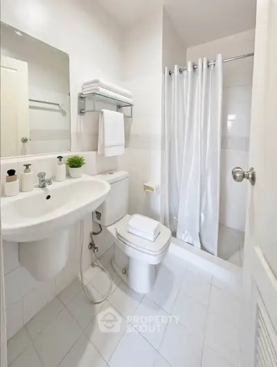 Modern bathroom with white tiles, shower, and sleek fixtures.