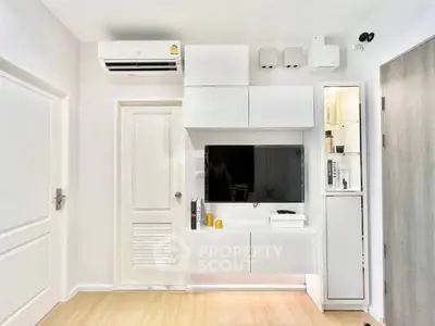Modern living room with sleek white cabinetry and mounted TV, featuring minimalist design and air conditioning.