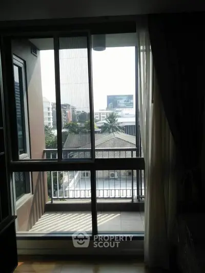 Bright apartment balcony with city view and large sliding glass doors.