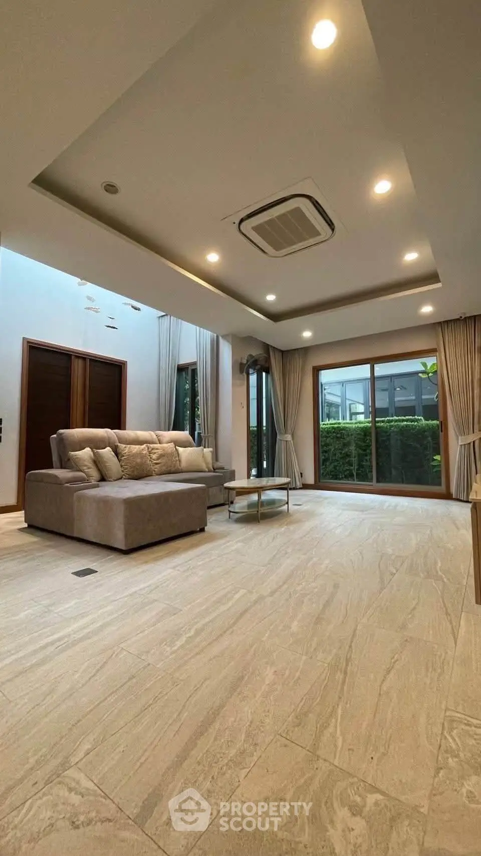 Spacious modern living room with elegant sofa and large windows overlooking a lush garden.