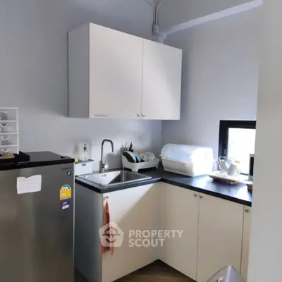 Modern compact kitchen with sleek cabinetry and stainless steel fridge