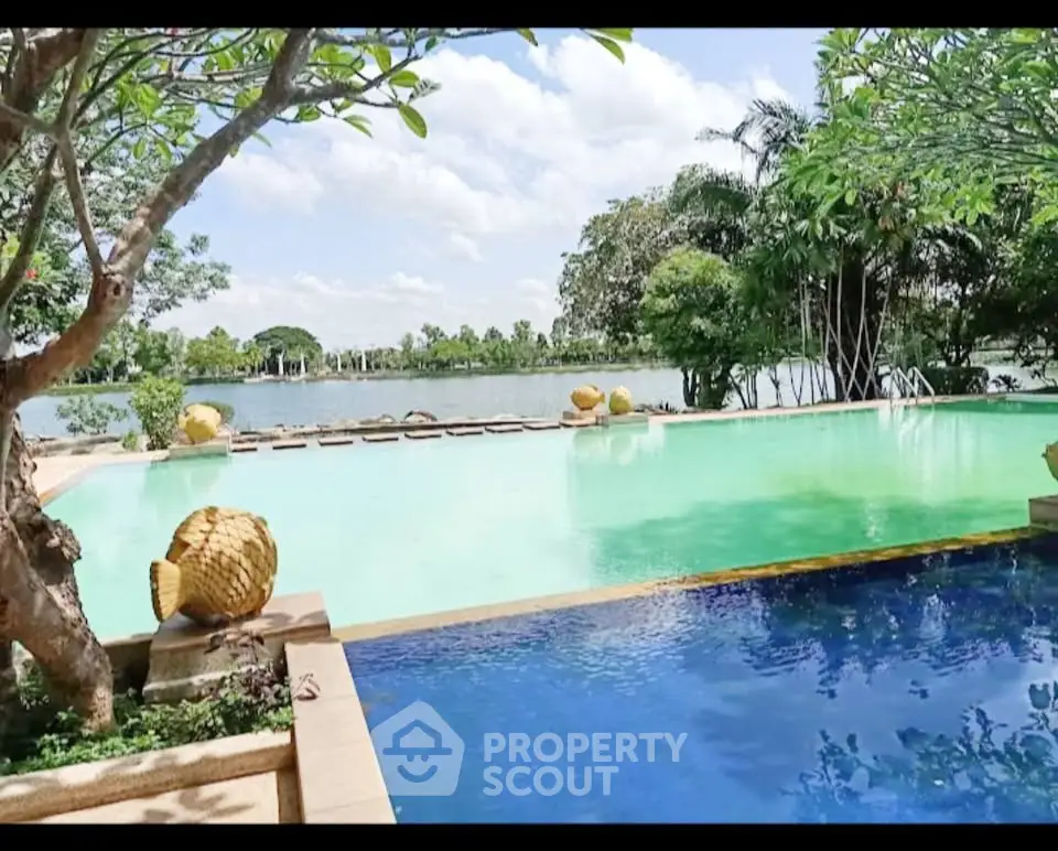 Luxurious poolside view with lush greenery and serene lake backdrop, perfect for relaxation and leisure.