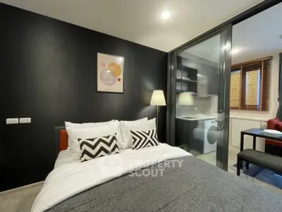 Modern bedroom with stylish decor and adjacent kitchen featuring washing machine.