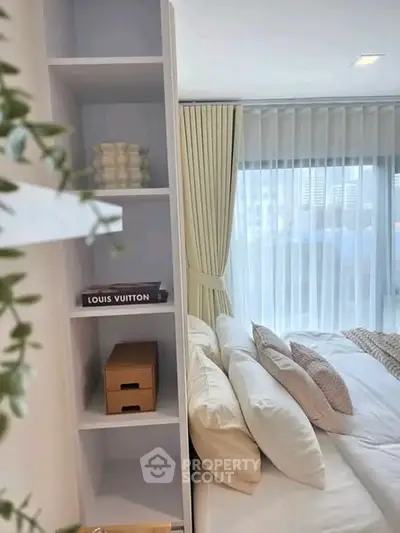Luxurious bedroom with elegant decor and city view, featuring stylish shelving and plush bedding.