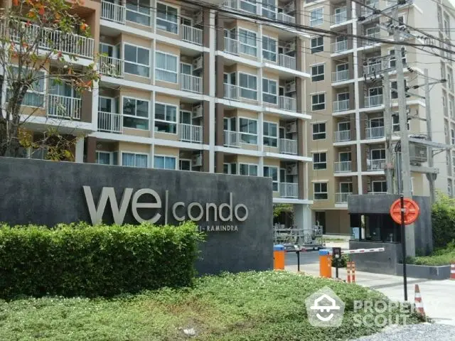 Modern condominium complex with lush landscaping and a prominent entrance sign, showcasing urban living with a touch of nature.