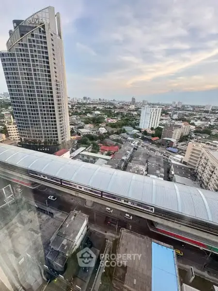 Stunning cityscape view from high-rise building with urban skyline and train station below.