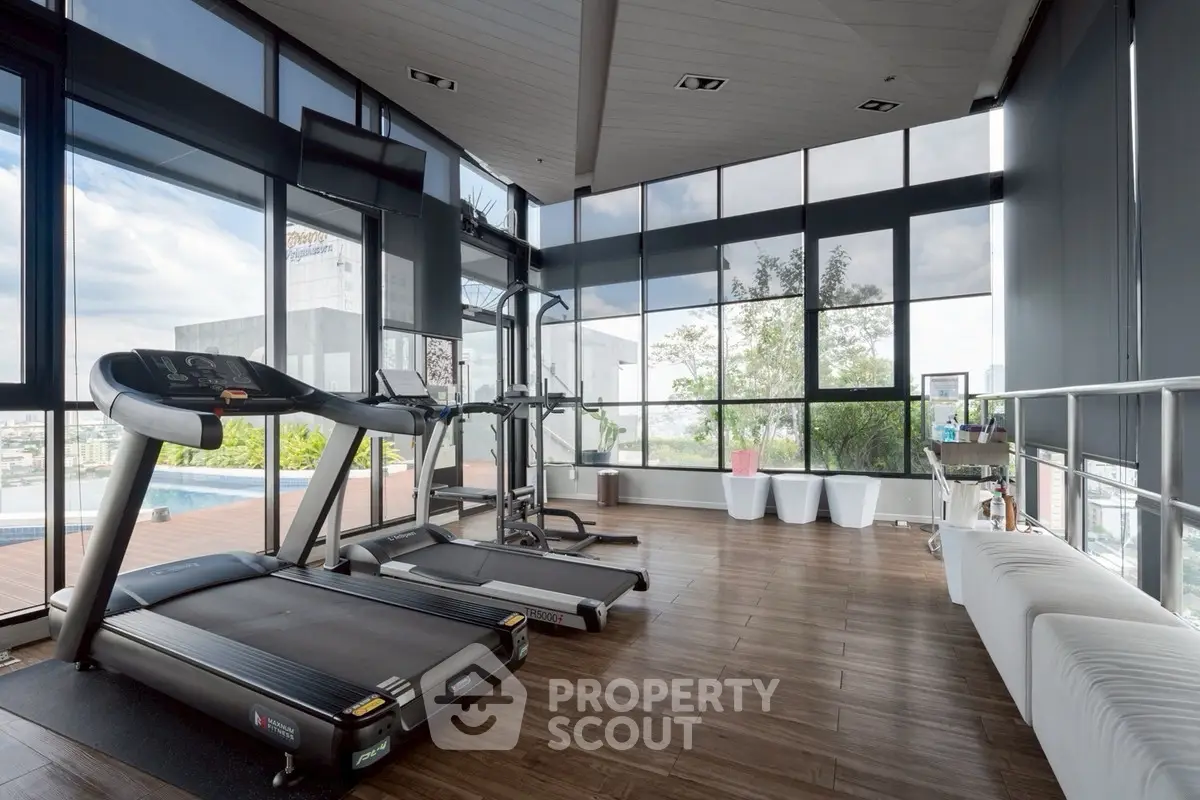 Modern gym with panoramic windows and state-of-the-art equipment in luxury real estate property.