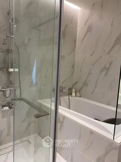 Luxurious modern bathroom with marble tiles and glass shower enclosure