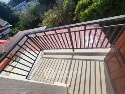 Charming balcony with metal railing overlooking lush greenery, perfect for relaxation and outdoor enjoyment.