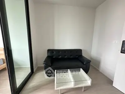 Modern minimalist living room with black sofa and glass coffee table