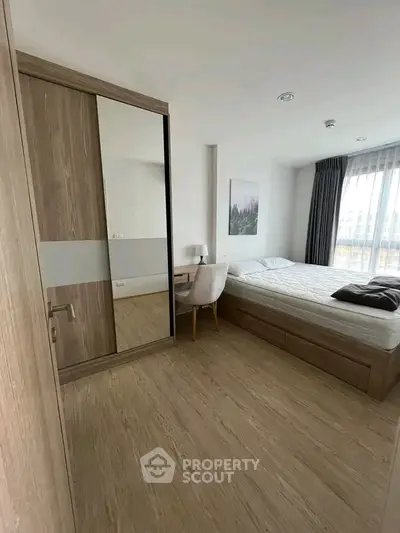 Modern bedroom with wooden flooring, large wardrobe, and natural light from window.