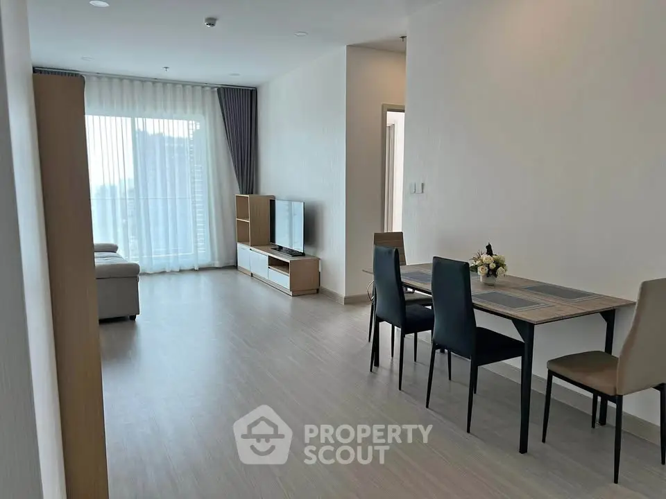 Spacious modern living room with dining area and natural light in a high-rise apartment.