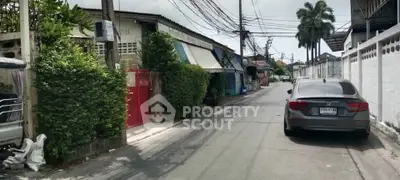 Charming residential street with lush greenery and parked car, showcasing suburban tranquility.