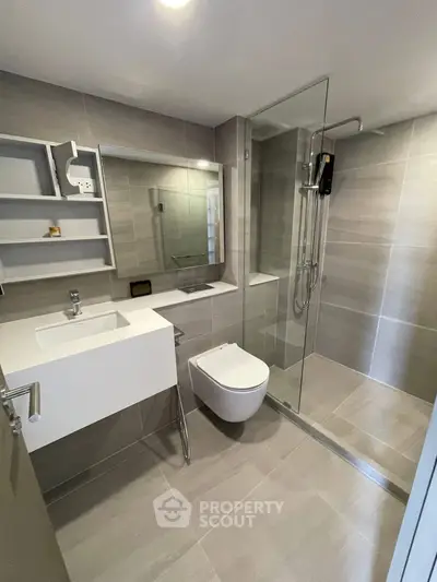 Modern bathroom with sleek design, featuring a glass shower enclosure and contemporary fixtures.