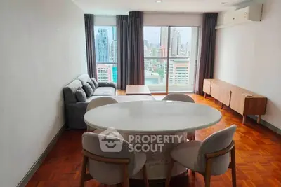 Spacious living room with city view, modern furniture, and wooden flooring in a high-rise apartment.