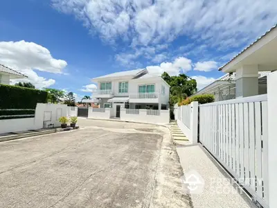 Stunning modern house with spacious driveway and lush greenery under a bright blue sky.