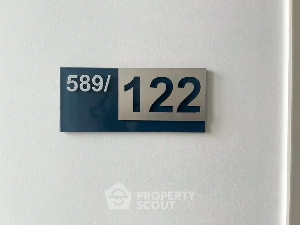 Modern apartment number sign on a white wall, showcasing sleek design.