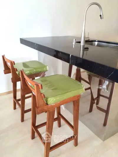 Modern kitchen with sleek black countertop and stylish wooden bar stools