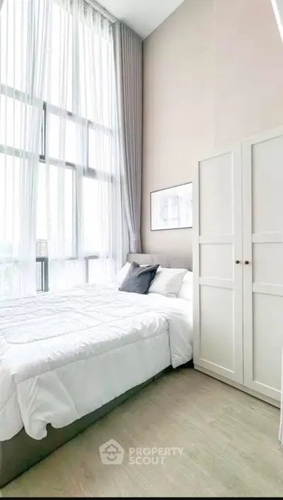 Bright and airy bedroom with high ceilings and large windows, perfect for modern living.