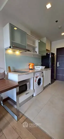 Modern kitchen with sleek appliances and washing machine in compact layout