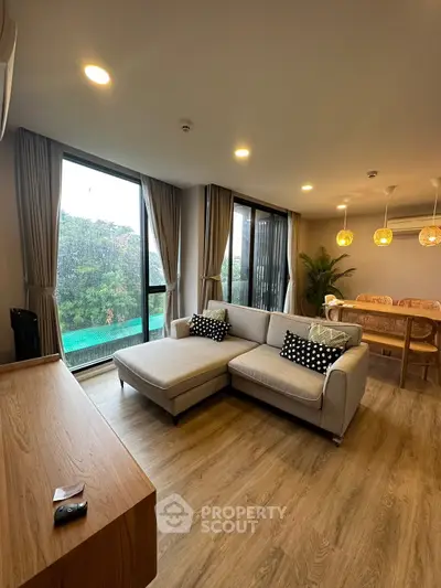 Spacious living room with modern decor and pool view, featuring a cozy sectional sofa and elegant dining area.
