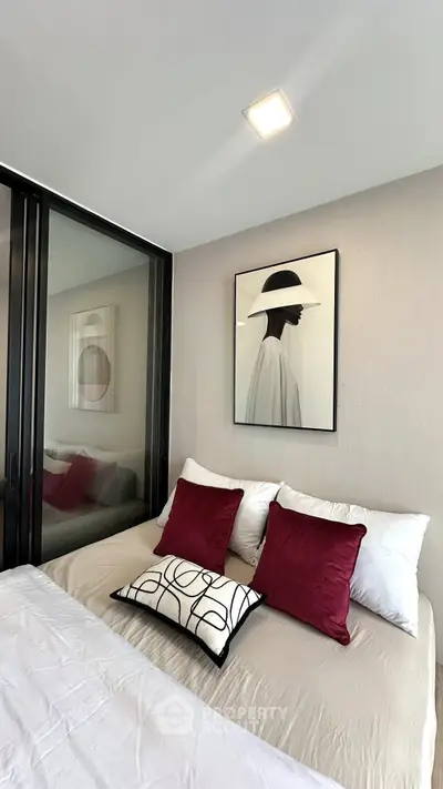 Modern bedroom with stylish decor and elegant artwork, featuring plush pillows and a cozy bed.
