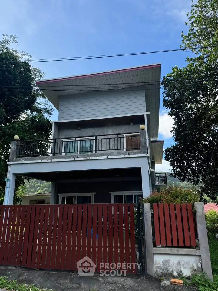 Modern two-story house with balcony and lush greenery