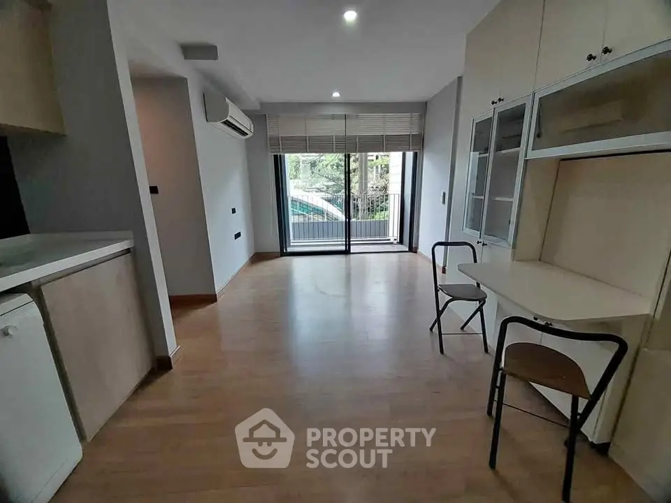 Spacious modern living room with balcony view and sleek wooden flooring.